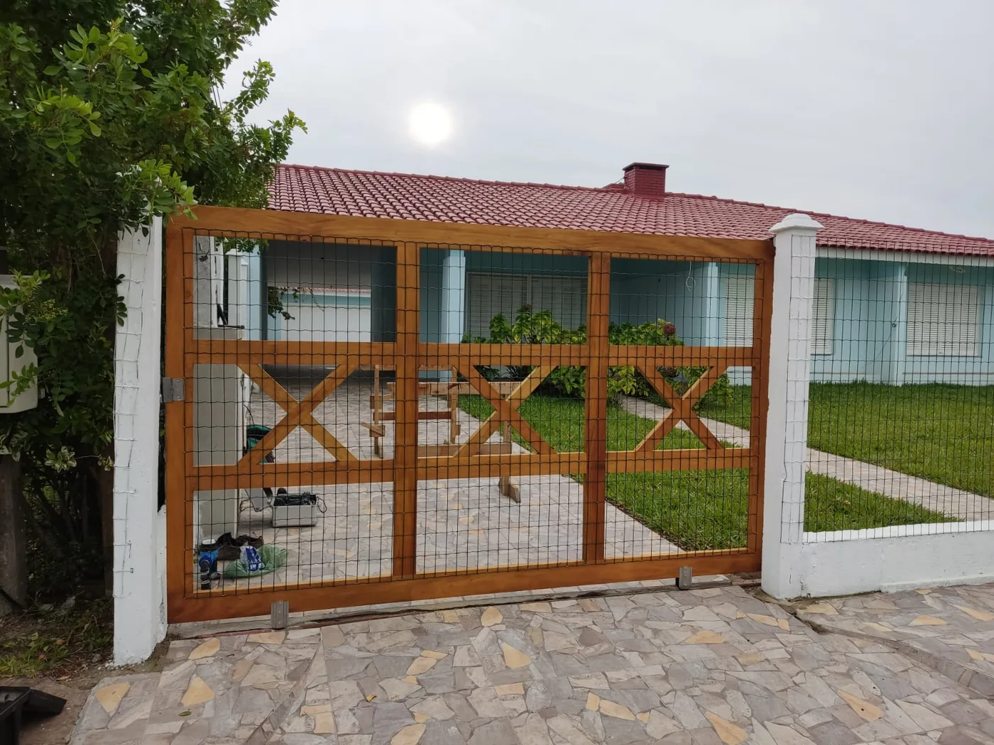Portão de madeira com tela instalado em residência